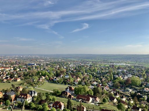 A panoramic view of a town with houses and gardens under the blue sky