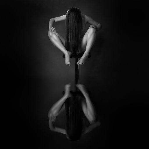 Mujer sentada mirando su reflejo, la composición manifiesta la sutileza de un reloj de arena