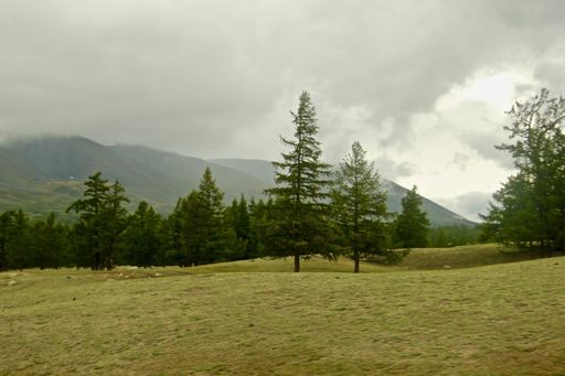 A beautiful landscape surrounded by mountains gleaming under the cloudy sky