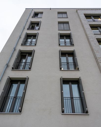A low-angle shot of an exterior of a modern multi-storey building, featuring a variety of windows