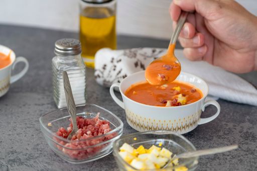 A closeup shot of a person taking a scoop from the delicious Salmorejo soup with a spoon