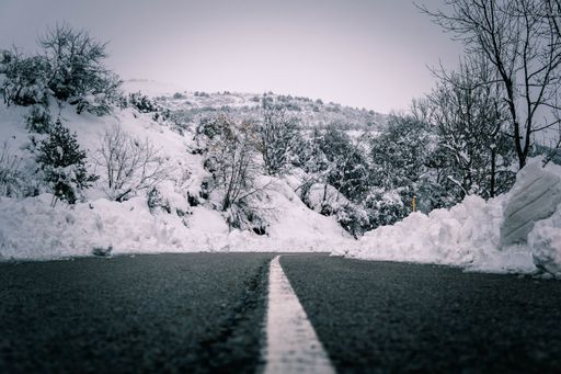 A beautiful view of a road surrounded by hills and trees covered in snow in winter