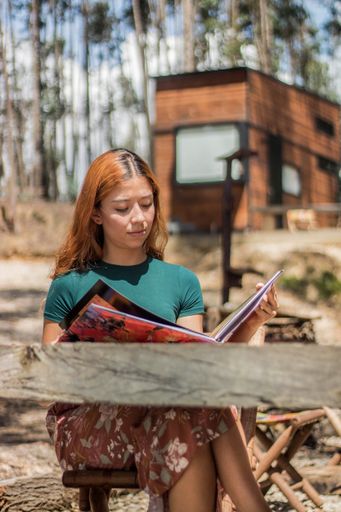 A pretty woman sitting outdoors and reading a journal on a blurry background