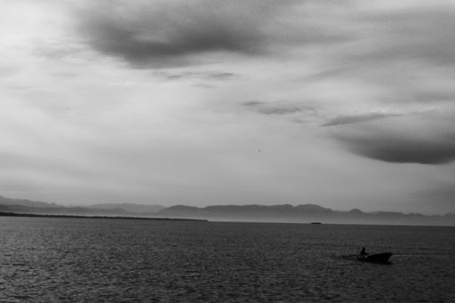 A grayscale shot of the tranquil sea under a cloudy sky on a gloomy day