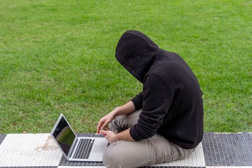 A young man sitting with a bad posture using his laptop and phone