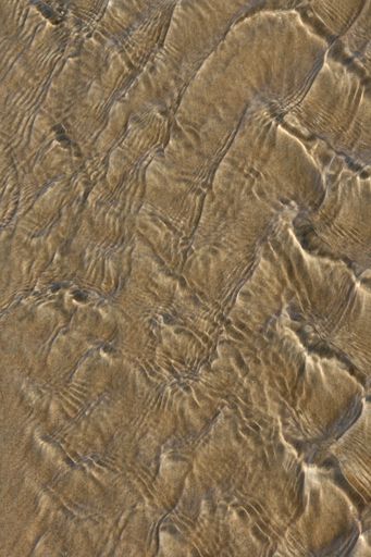An abstract effect of water movement on a sandy bottom with sunny reflections