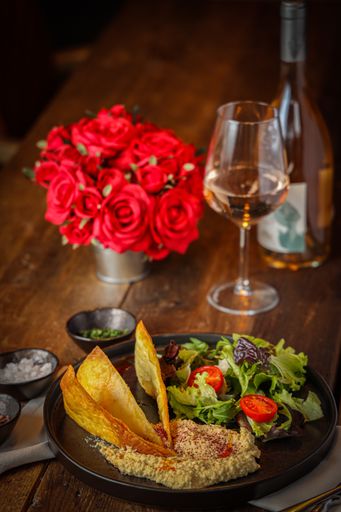 A vertical shot of hummus served with salad on a black plate