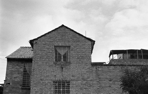 A low angle grey scale shot of an old brick building under the cloudy sky
