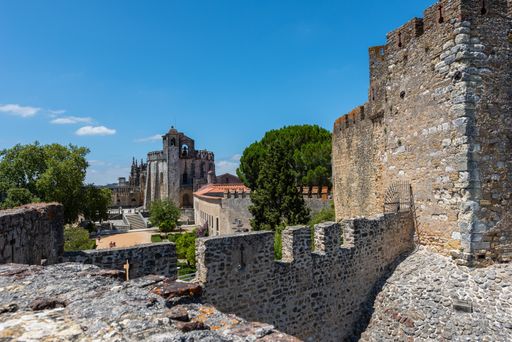 The Templar castle surrounded by greenery under sunlight and a blue sky in Tomar in Portugal