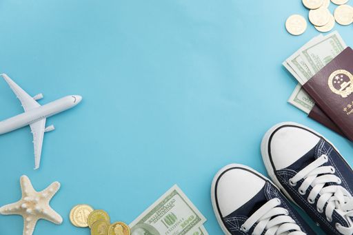 A top view of money, passports, starfishes, a toy airplane on a blue background - vacation concept
