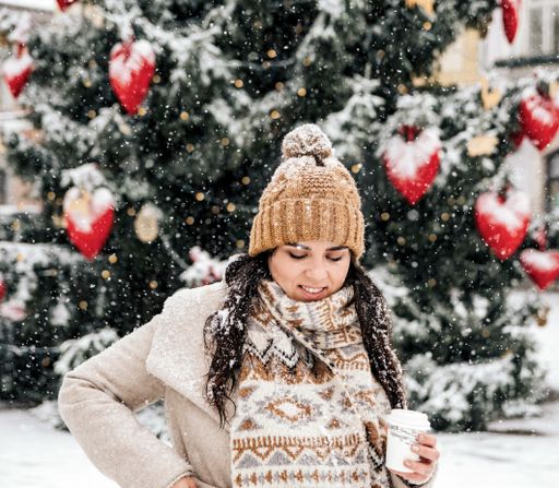 A woman holding coffee in front of a Christmas tree -
