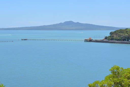 View of Okahu Bay Wharf and Sea View Bridge at Tamaki Drive with Rangitoto dormant volcano island in background