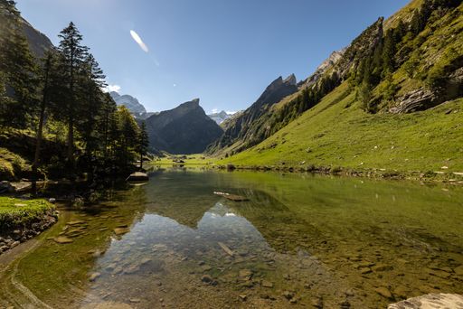 A breathtaking view of evergreen mountains surrounding a tranquil lake against a blue sky