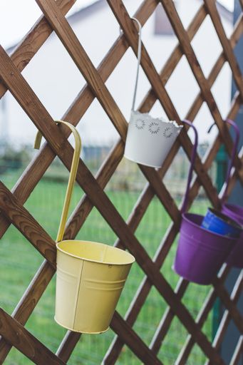 A vertical shot of metallic flowerpots hanging on a wooden gate