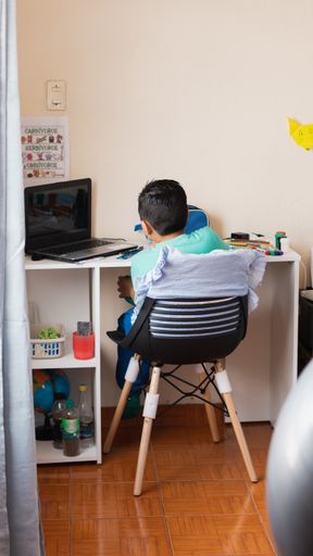 A high angle shot of a Hispanic child studying at home