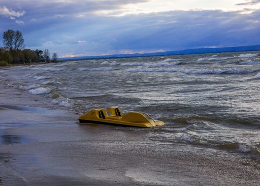 A small boat floating in the sea during the sunset, captured from the beach