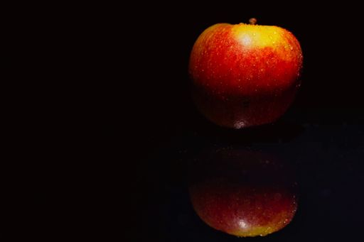 A shot of an apple on a dark surface with reflection - still life photography