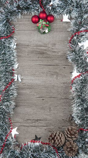A vertical shot of a wooden board with Christmas ornaments as a fram