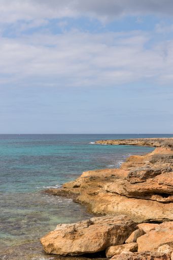 A vertical shot of the rocky beach and the endless ocean captured in Mallorca, Spain