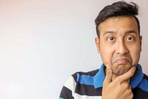 A portrait of a handsome middle-aged Indian male with a striped shirt making a funny face