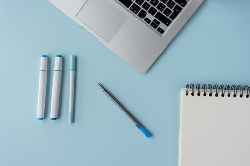 A top view of a student's desk with a laptop, a notepad, and other studying supplies