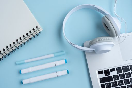 A top view of a student's desk with headphones, a notepad, and other studying supplies