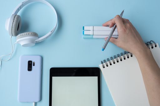 A top view of a student's desk with a phone, a notepad, and other studying supplies