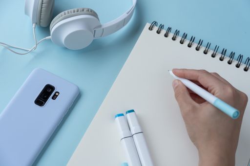 A top view of a student's desk with a phone, a notepad, and other studying supplies