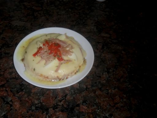 A closeup shot of a humita maize pizza on a white plate with a dark granite background. Copyspace.