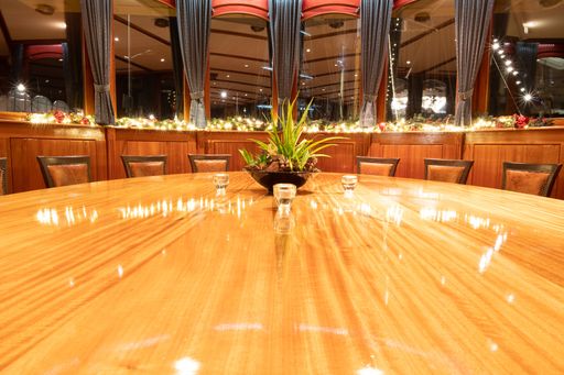A high angle shot of a fancy restaurant with a round wooden table with windows and curtains behind