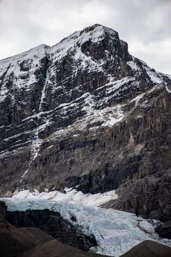 A vertical shot of a beautiful cloudscape over snow-covered rough rock formations in the countryside