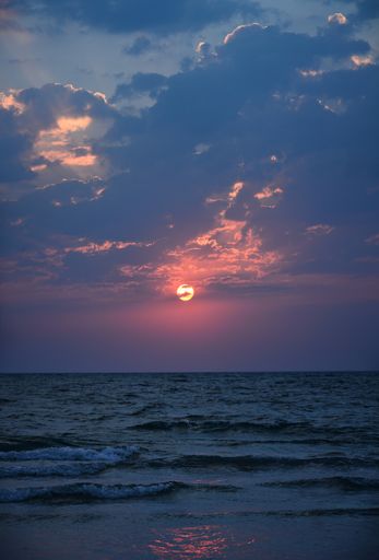 A vertical shot of the calm sea and picturesque cloudscape, blue and pink sunrise scenery