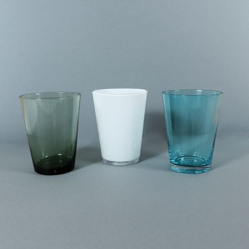 A vertical shot of white, green, and blue glasses isolated on a gray background