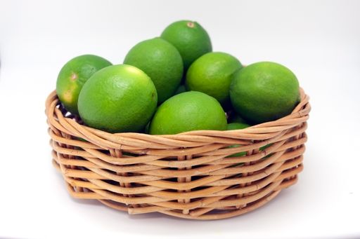 A basket with green limes isolated on white background