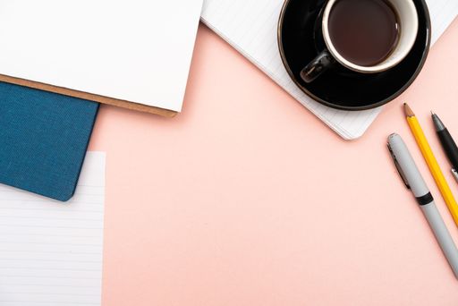 Office Supplies Over Desk With Keyboard And Glasses And Coffee Cup For Working Remotely, Assorted School Utilities With Hot Drink And Eyeglasses.