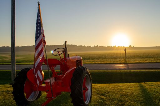 A closeup of a patriotic international Farmall tractor with the US flag at sunrise