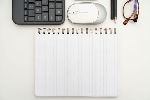 Office Supplies Over Desk With Keyboard And Glasses And Coffee Cup For Working Remotely, Assorted School Utilities With Hot Drink And Eyeglasses.