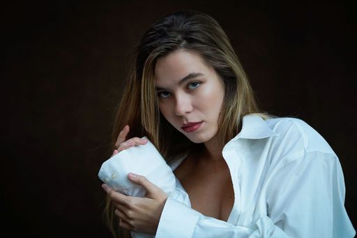 A portrait of a sexy Caucasian blonde in a man's shirt with a serious look
