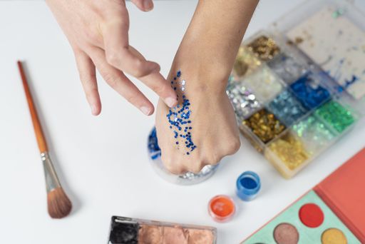 A selective focus shot of a person using crystal blue glitters on her hand