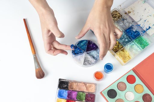 A high angle shot of a person using crystal blue glitters on her finger from a palette