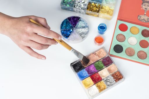 A selective focus shot of a hand using a brush on a watercolor palette with glitters