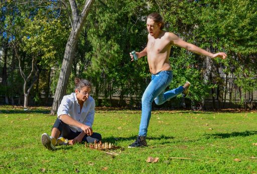 A closeup shot of two men in the garden with chessboard, one man kicks the board with his leg, defeat