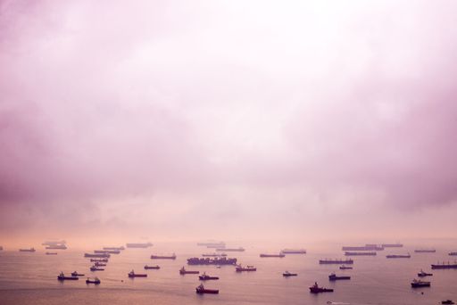 The beautiful view of the pinkish sky and sea with ships at sunset. Singapore.