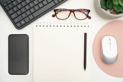 Office Supplies Over Desk With Keyboard And Glasses And Coffee Cup For Working Remotely, Assorted School Utilities With Hot Drink And Eyeglasses.