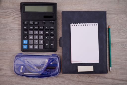 Blank Notebook Page With A Calculator And Geometric Stationery. Empty Lined Notepad With Calculation Compass Office Supplies Over Desk.