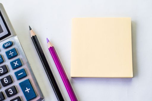 Plain Spiral Notebook With Pen Beside Calculator And Coins On Table. Simple Notepad And Ballpen Alongside Calculation Machine Placed On Top Of Desk.