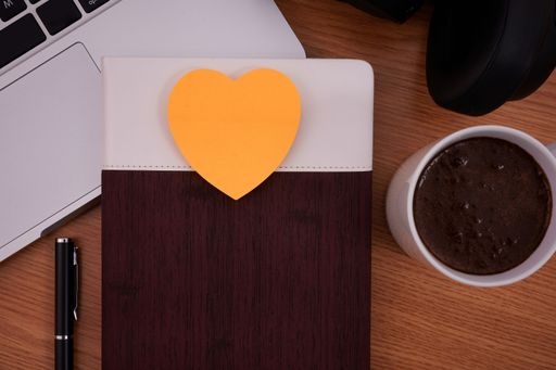 Blank Notepad Over Laptop With Cup Of Warm Coffee. Empty Journal On A Notebook Computer With A Ballpen And Headset Close To Mug Of Hot Drink.