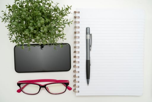 Office Supplies Over Desk With Keyboard And Glasses And Coffee Cup For Working Remotely, Assorted School Utilities With Hot Drink And Eyeglasses.