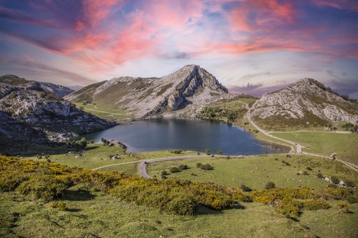 A mesmerizing view of the Lake Enol gleaming under the pink cloudy sky in  Asturias, Spain