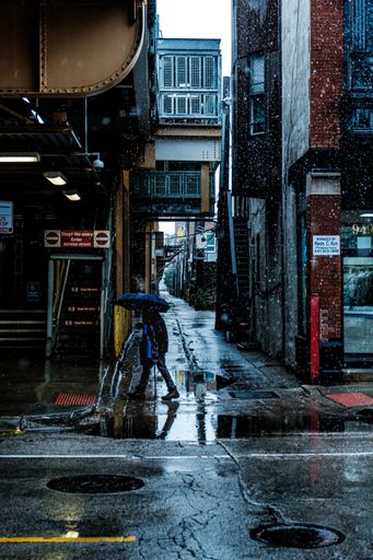 dA vertical shot of a person walking with an umbrella on a snowy day